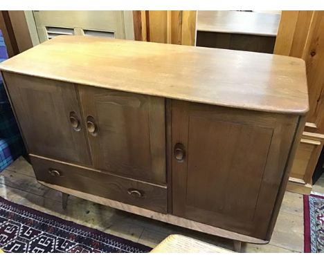 An oak Ercol sideboard, the shaped top with moulded edge above an arrangement of three panel doors and single drawer, with sh