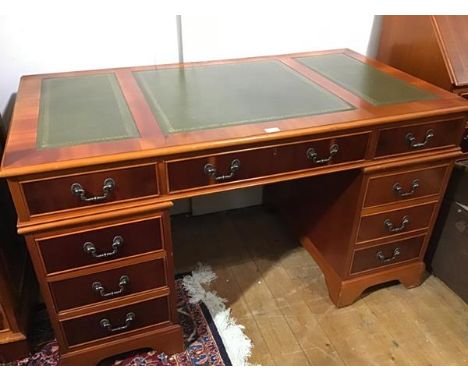 A yew wood reproduction twin pedestal kneehole desk, the top with inset leather skiver and centre frieze drawer, flanked by a