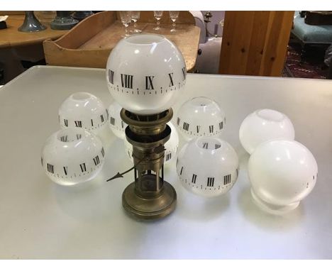 An Edwardian brass clockwork night light lamp with single hand and opaque glass globes, with roman hour markers, complete wit