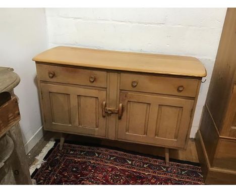 An Ercol light ash sideboard, the shaped top with moulded edge above two frieze drawers and two inset panel doors, raised on 