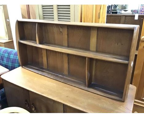 An Ercol oak and elm wall shelf with an arrangement of four sections on shaped side supports (h.50cm x 107cm x 12cm)