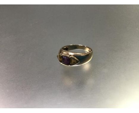 A 9ct gold three stone ring, the centre cushion cut amethyst flanked by triangular citrines, mounted in rubover setting (3.73