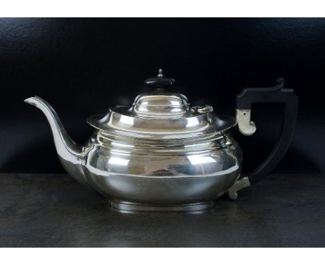 A silver teapot, W F Mitchell, Birmingham 1935, of plain polished oval form with ebonised handle and finial, 14cm high, weigh