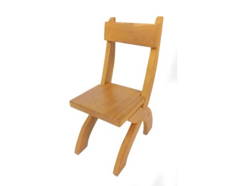 A light oak single chair, raised on an X frame support.