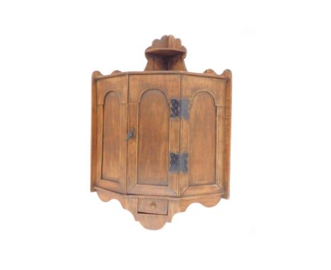 A rustic plywood corner kitchen cupboard, with a single drawer opening to reveal a small internal shelf, above a spice drawer