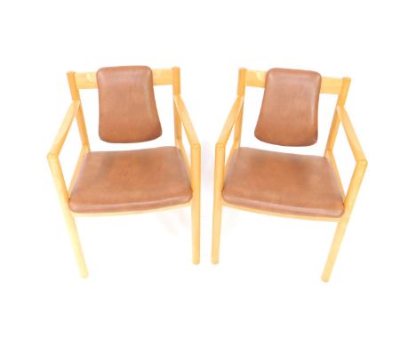 A pair of Ercol beech carver chairs, with brown rexine headrest and overstuffed seat, raised on turned legs.