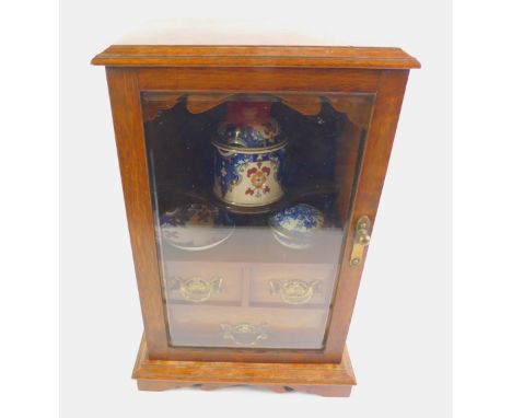 A Victorian oak smoker's cabinet, with a bevelled glass door opening to reveal a serpentine shelf above two short and one lon