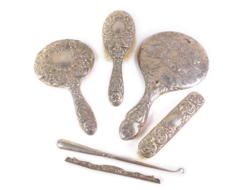 A silver backed hand mirror clothes and hair brush, embossed with masks birds and scrolling leaves, Birmingham 1984, a silver