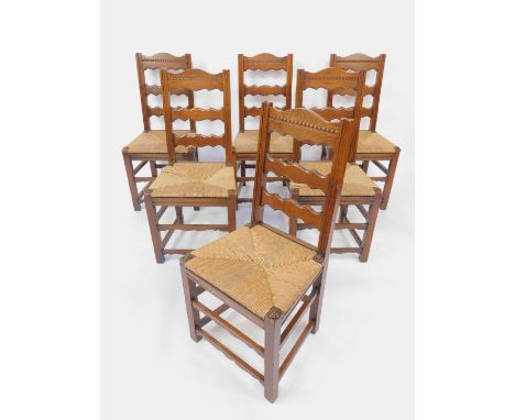A set of six oak country ladder back dining chairs, with rush seats, raised on square legs united by stretchers.