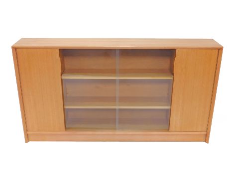 A Gibbs 1970's teak sideboard, with two glazed doors opening to reveal two shelves, flanked by two doors, each enclosing a si