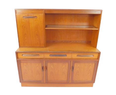 A G-Plan teak sideboard, with a drop down door enclosing a mirror back drinks cabinet, flanked by one single shelf, over thre