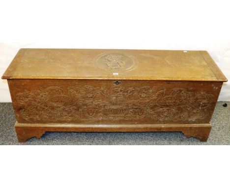 Carved oak blanket box with entwined vignette, the front panel with peacock and urn decoration raised on bracket supports