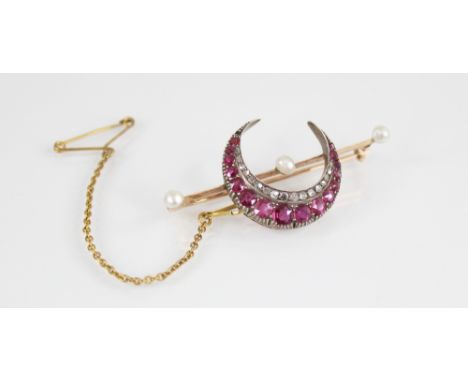 An Edwardian ruby, diamond and pearl crescent brooch, set with graduated oval mixed cut rubies and rose cut diamonds, upon a 