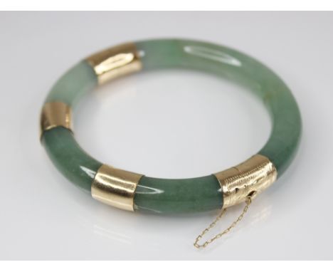 A jade hinged bangle, of plain polished circular form, with 14ct gold mounts, import marks for Edinburgh 1998, 7.7cm diameter