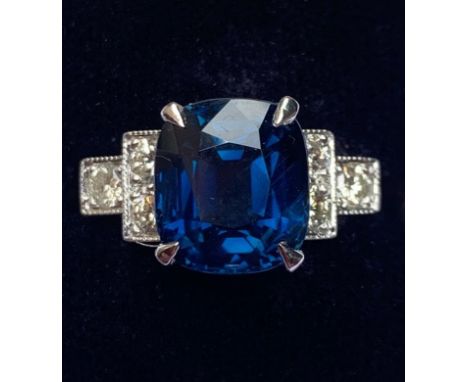 An Art Deco sapphire and diamond ring, the central rectangular cushion cut blue sapphire measuring 11.6mm x 10.6mm x 6.0mm (w