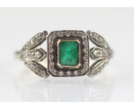 An early 20th century emerald and diamond ring, the central rectangular step cut emerald measuring 5mm x 3.5mm, with a border