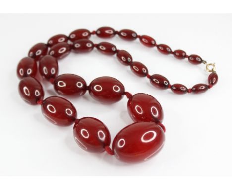 A cherry amber bead necklace, comprising twenty-seven polished oval amber beads, measuring between 12mm x 9mm and 36mm x 25mm