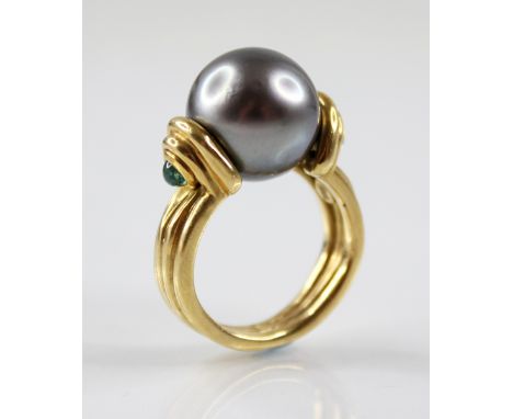 A Tahitian pearl and emerald 18ct gold cocktail ring, the central spherical pearl measuring 12.5cm diameter, set to stepped s