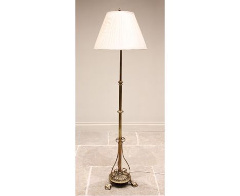 An early 20th century brass telescopic standard lamp, the adjustable column extending to a lobed circular plinth base and thr