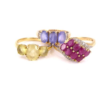 Three 9ct yellow gold dress rings to include a ruby and tiny diamond chip crossover ring, size S, a three-stone ring set with