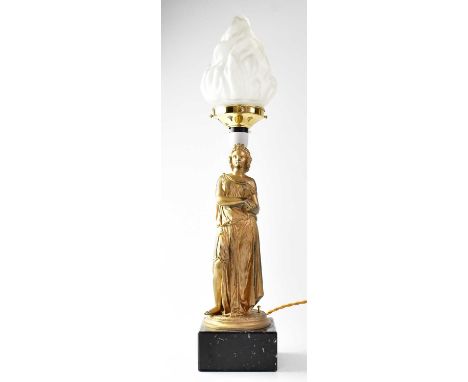 A painted spelter figural lamp base with frosted glass torch shade, raised on a black hardstone plinth with canted edges, hei