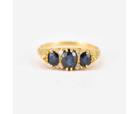 An 18ct gold sapphire and diamond ring in a typical Victorian-style mount, the three graduated claw set sapphires separated b