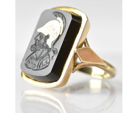 A 9ct gold ring with engraved black stone panel depicting a Greek warrior with yellow metal inlaid helmet, size I, approx. 6.