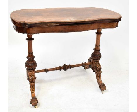 A burr walnut shaped fold-over card table raised on carved turned columns to stretchered outswept feet and castors, 74 x 95 x