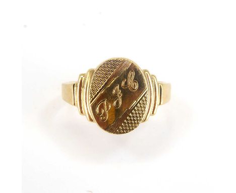 A gentlemen's 9ct Art Deco style signet ring, the oval top with diagonal band of initials, 'PJC', engine turned decoration an