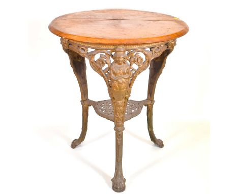 An early 20th century Britannia pub table with circular wooden top,  three cast iron supports to claw feet, and under shelf, 