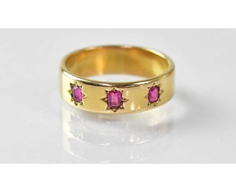 An 18ct gold wide band ring, star set with three small rubies, size N, approx. 5.7g.Condition Report: Middle ruby significant