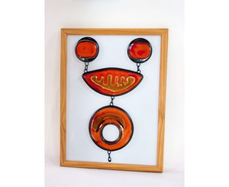 A Poole pottery Delphis design plate, with two small circular orange pieces of pottery, an oval-shaped centrepiece with orang
