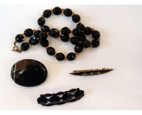 Black onyx oval brooch, black enamel and seedpearl bar brooch, French jet brooch and a black faceted necklace (4) 