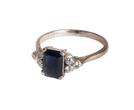 An 18ct white gold, sapphire and diamond set ring, claw set with the cut cornered rectangular step cut sapphire at the centre