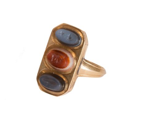 A gold ring, the cut cornered rectangular front mounted with three carved oval agate intaglios, ring size L, with a box.  Ill