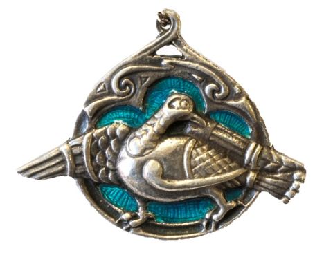A silver and turquoise coloured enamel pendant brooch, designed as a bird with outspread wings, on a blue enameled ground wit