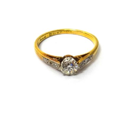 A gold and platinum, diamond set ring, claw set with the principal circular cut diamond at the centre, between diamond set th