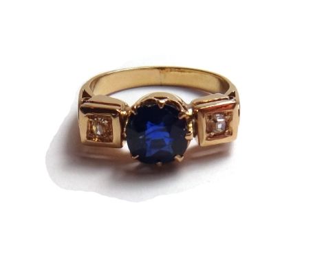 A gold, sapphire and diamond set three stone ring, claw set with the cushion shaped sapphire at the centre, between two cushi