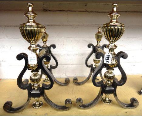 A pair of Georgian steel and brass mounted fire dogs, each with turned twin urn finials and fluted cross member on scroll fee