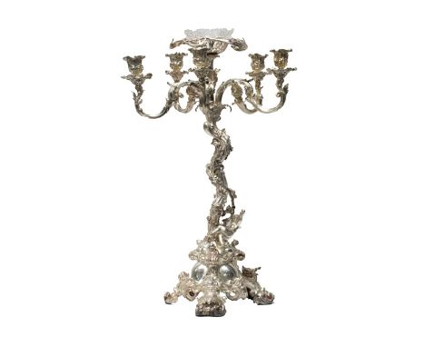 An Elkington & Co plated table centrepiece stand, of rococo rustic form, with putto supports, scrolling arms and on a triform