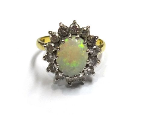 An 18ct gold, opal and diamond set oval cluster ring, claw set with the oval opal at the centre, within a surround of circula