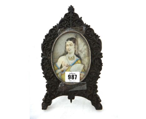 An Indian miniature oval painting on ivory, 20th century, painted with a half length portrait of a young woman holding a fan,