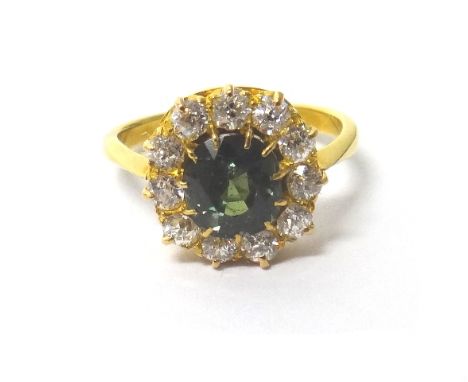 A gold, diamond and green sapphire set cluster ring, claw set with the cushion shaped green sapphire at the centre, within a 