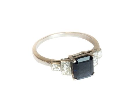 A sapphire and diamond set ring, claw set with the cut cornered rectangular cut sapphire at the centre, between square cut di