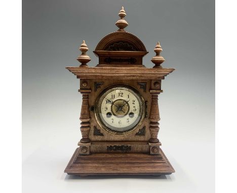 A German walnut and metal mounted mantel clock, with turned finials and cream enamel chapter ring, striking on a coiled gong,
