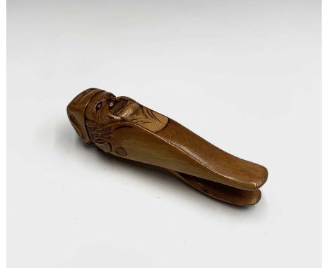 A treen nutcracker, early 20th century, carved as a smiling gent wearing a cap, length 15.5cm.