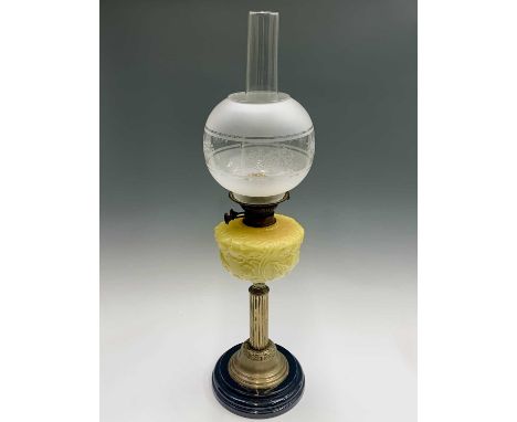 A Victorian brass oil lamp, with fluted shaft, the pedestal having embossed floral decoration, with yellow moulded glass rese