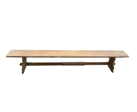 A pine bench or form, 19th century, raised on shaped angled end supports, width 229cm.