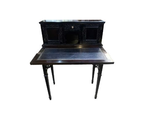 An ebonised bonheur de jour, circa 1900 in Chinese chippendale style, with a central drawer opposed by doors, the hinged fron