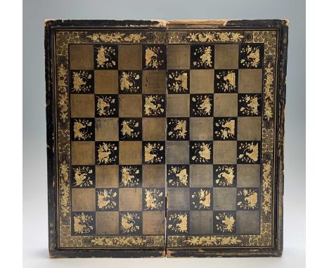 A Chinese lacquer folding chess board, circa 1900, with gilt heightened decoration of figures and buildings, the interior for